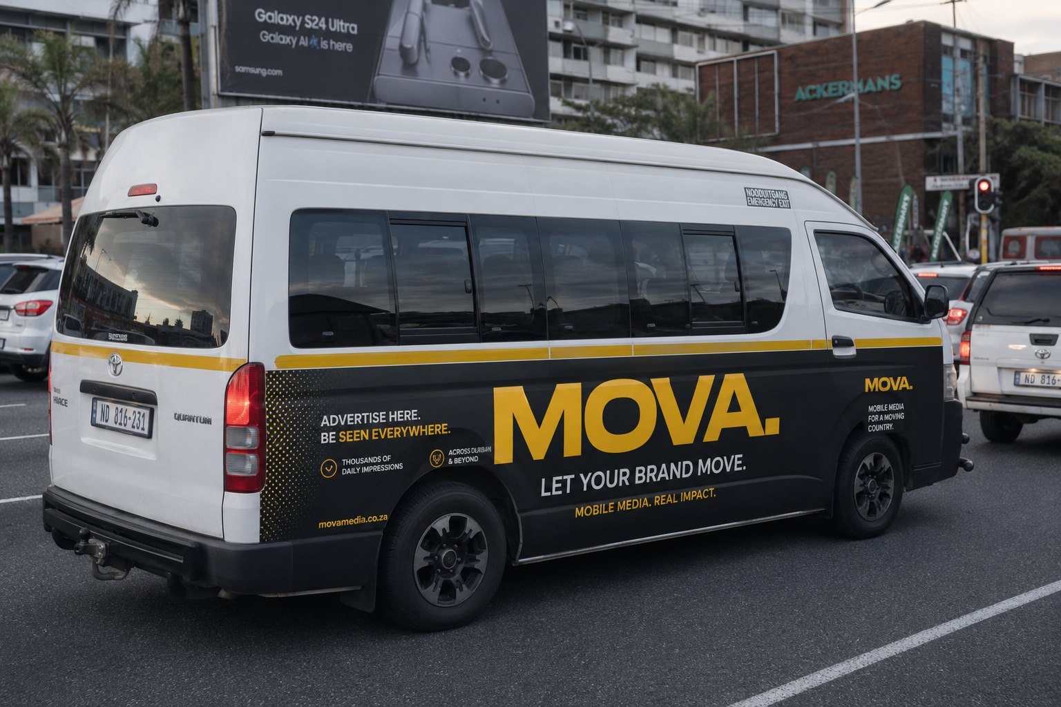 Side profile of a white Toyota Quantum minibus with MOVA side-panel branding in South African traffic